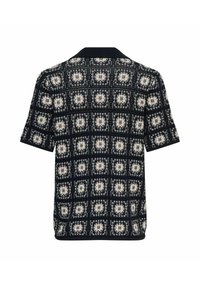 Chemise en tricot noire à manches courtes avec un motif géométrique carré blanc et gris et un col noir uni, vue de dos.