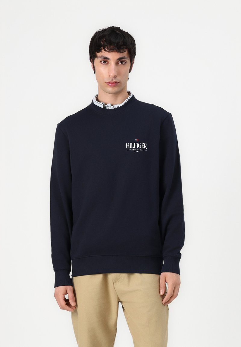 Marineblauwe katoen sweatshirt met lange mouwen, ronde hals en geborduurde "HILFIGER" logo op de borst; gladde textuur en ribbelboorden.