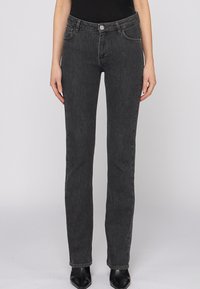 Jeans de mezclilla negra con corte ajustado, cinco bolsillos y cierre de botón. Textura suave y detalle de costura mínima.