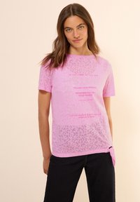 Camiseta de manga corta rosa con un patrón de estampado de leopardo y acentos de texto. Tejido ligero con un detalle de moño en el dobladillo lateral.
