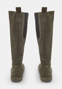 Oluļzaļas zamša ceļgala zābakos ar teksturētu apdari, sānu rāvējslēdzējiem un kontrastējošu beigtu zoli ar smalku rakstu.