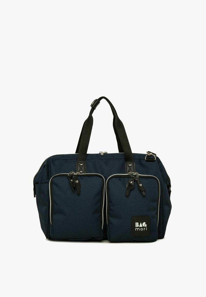 Mornarska platnena torba za prtljago z dvema sprednjima žeprenj poštnicama, črnimi detajli, trdnimi naramnicami in pravokotno obliko. Ima blagovno znamko logo na sprednji strani.