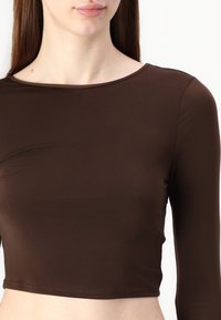 Brun langermet crop topp laget av glatt, elastisk stoff med en bred hals og tettsittende silhuett. Enfarget design, ingen synlige mønstre.