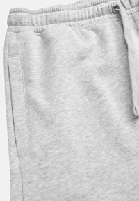 Graue Baumwoll-Sweatpants mit einer weichen Textur, einem elastischen Taillenbund und einer Seitentasche. Der Stoff hat ein meliertes Aussehen.