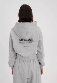 Grijze hoodie met een grote capuchon, elastische boorden en een taillekoord. Voorzien van een zwart tekstlogo op de rug, gemaakt van zachte, gestructureerde stof.