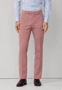 Slim-fit, ljusrosa bomullbyxor med platt front, en knapp och sidofickor. Bärs med mörka dresskor och en ljusblå skjorta.