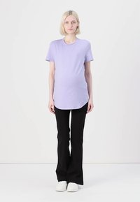 Lys lilla gravidy t-skjorte med korte ermer og buet hem, kombinert med svarte flagrende bukser og hvite joggesko. Enkel design.