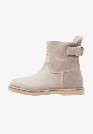 Suede ankle boot in light gray with a rounded toe, strap and buckle accent on the side, and a rubber sole with a natural trim.