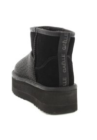 Stivali neri alla caviglia con tomaia in suede e tessuto testurizzato, dotati di una spessa suola piattaforma e di un'etichetta posteriore con marchio per un facile utilizzo.