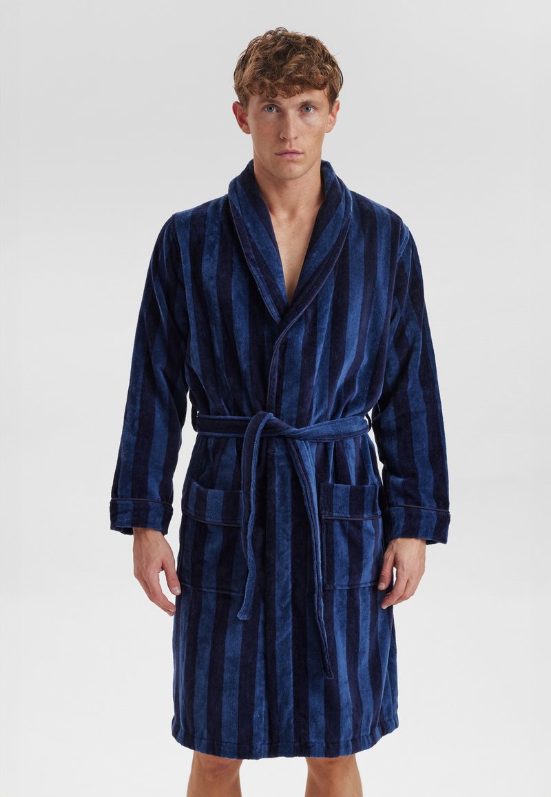 Accappatoio in spugna a righe blu navy con colletto sciallato, due tasche anteriori e cintura regolabile. Texture morbida e design di lunghezza media.