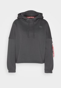 Ciemnoszara krótka bluza z kapturem na sznurki, ściągaczami na rękawach oraz kieszenią na zamek. Posiada czerwoną metkę z napisem "REMOVE BEFORE FLIGHT".