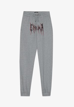 Graue Sweatpants aus weichem Material mit schmalem Bund, die auf der Vorderseite mit einem schwarzen und roten Grafikdruck "ENIGMA" bedruckt sind.