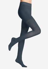 Gambe che indossano collant grigi scuri con motivo, un piede piatto e l'altro sollevato dietro con il ginocchio piegato.