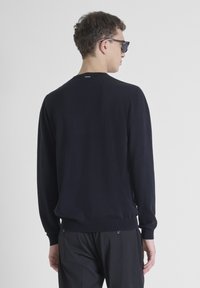 Mornarska pletena sv sweater sa dugim rukavima, rebrastim obrubom i manžetama, minimalistički dizajn, bez uzorka, prikazana sa stražnje strane.