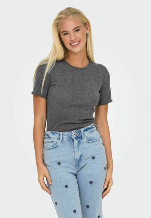 Grå tætsiddende t-shirt med korte ærmer og bølgede kanter. Sammen med lyseblå jeans, der har små sorte hjerte-mønstre og en denim struktur.