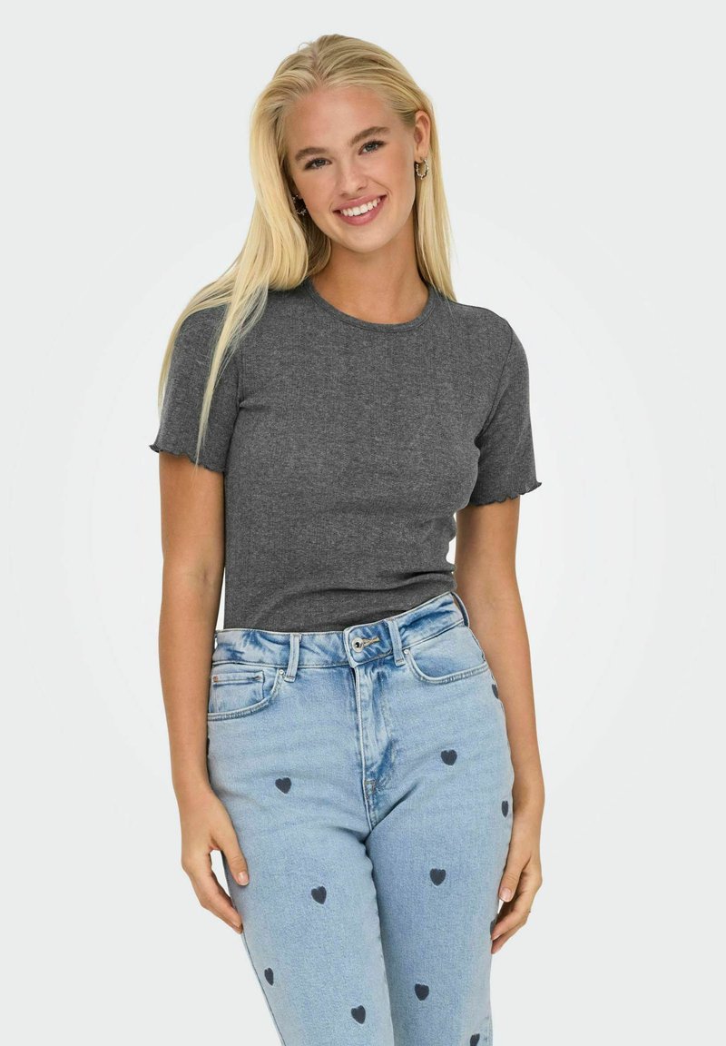 Grå tætsiddende t-shirt med korte ærmer og bølgede kanter. Sammen med lyseblå jeans, der har små sorte hjerte-mønstre og en denim struktur.