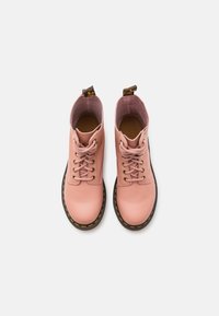 Pink leather ankle boots with round toes, eight eyelets, and tonal laces. Black rubber soles feature yellow stitching; pull tabs on the heels.