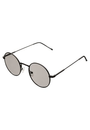 Gafas de sol redondas con un delgado marco de metal negro, lentes grises, almohadillas nasales transparentes y patas finas negras.