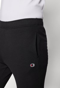 Svarta sweatpants i mjukt tyg med en liten broderad logotyp på vänster ficka. Inkluderar sidofickor och har en bekväm passform.