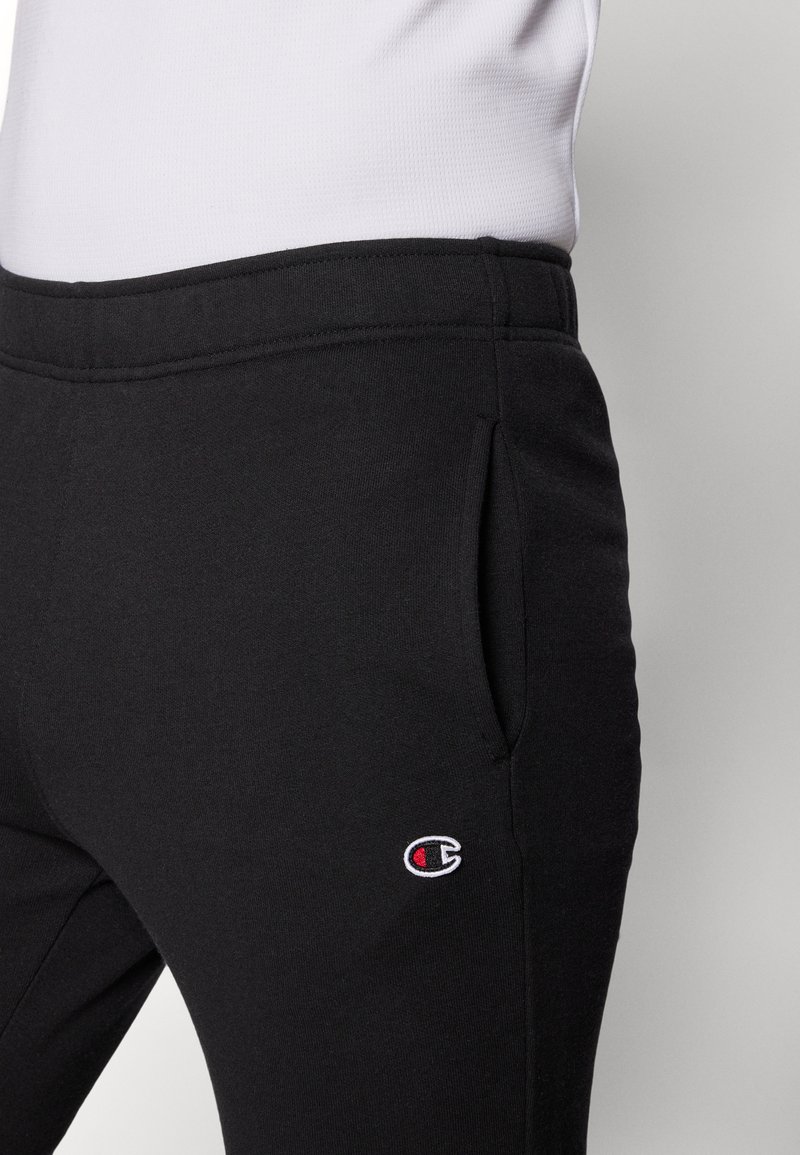 Pantaloni sportivi neri realizzati in tessuto morbido, con un piccolo logo ricamato sulla tasca sinistra. Presentano tasche laterali e una vestibilità comoda.