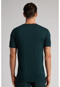 Ciemnozielona koszulka z krótkim rękawem, wykonana z miękkiego i elastycznego materiału. Posiada okrągły dekolt i gładką fakturę, zaprojektowana z myślą o dopasowanej sylwetce.