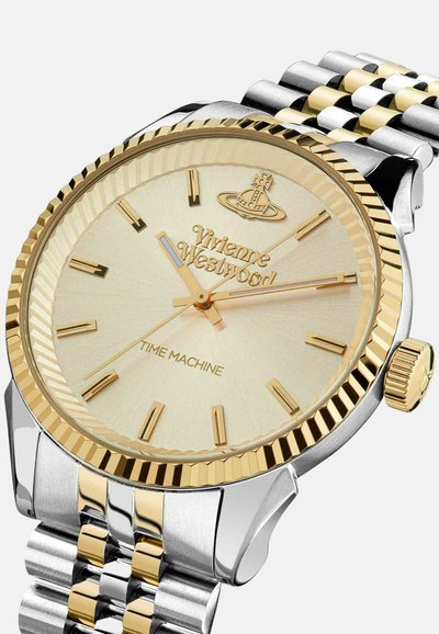 Rond analoog horloge met een goudkleurige lunette, gestructureerde gouden wijzerplaat, zilver- en goudkleurige roestvrijstalen armband en merklogo.