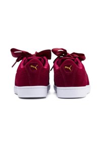 Maroon suede sneakers with satin bow laces, white rubber soles, and gold logo accents on the heel and side. Smooth texture overall.