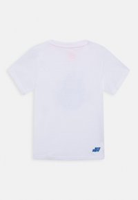 Camiseta blanca de algodón con mangas cortas, escote redondo y un pequeño acento de logo azul en la parte inferior derecha. Tono rosa sutil en la parte posterior.