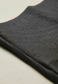 Black textured fabric with a geometric pattern, closely woven, featuring a smooth finish and a soft, flexible edge.