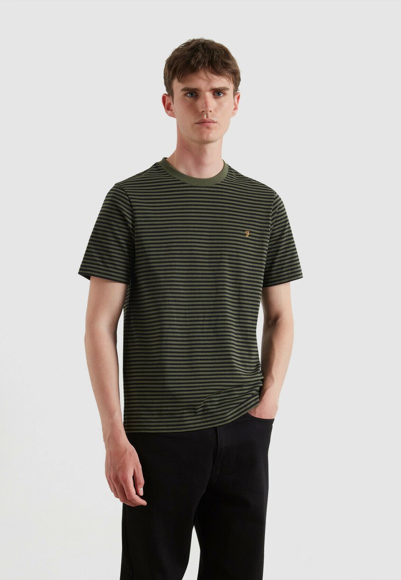 Camiseta de manga corta a rayas verdes y negras con cuello redondo acanalado y pequeño logotipo dorado en el pecho. Material de algodón suave.