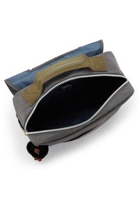Sac gris et bleu avec une fermeture à glissière, tissu texturé, anse en nylon et un porte-clés noir en fourrure. L'intérieur est doublé de matériau bleu foncé.
