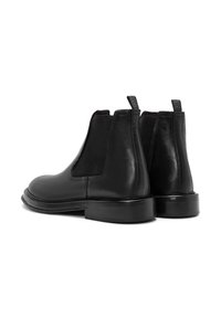 Botas Chelsea de cuero negro con paneles laterales elásticos, punta redonda y tacón bajo apilado. Asa texturizada con un patrón en espiga.