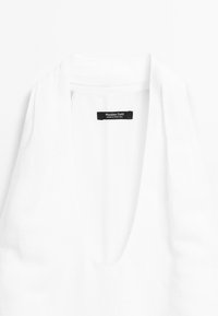 Top sans manches blanc avec un décolleté en V profond, fabriqué en tissu léger. Présente une étiquette noire avec l'inscription "Massimo Dutti" à l'intérieur du col.