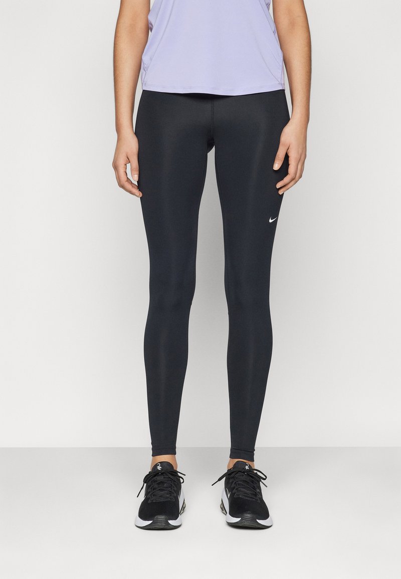 Crne tajice od rastezljivog materijala, prilagodljivog dizajna, s malim bijelim Nike logotipom na lijevom bedru, uparene s crnim sportskim tenisicama.