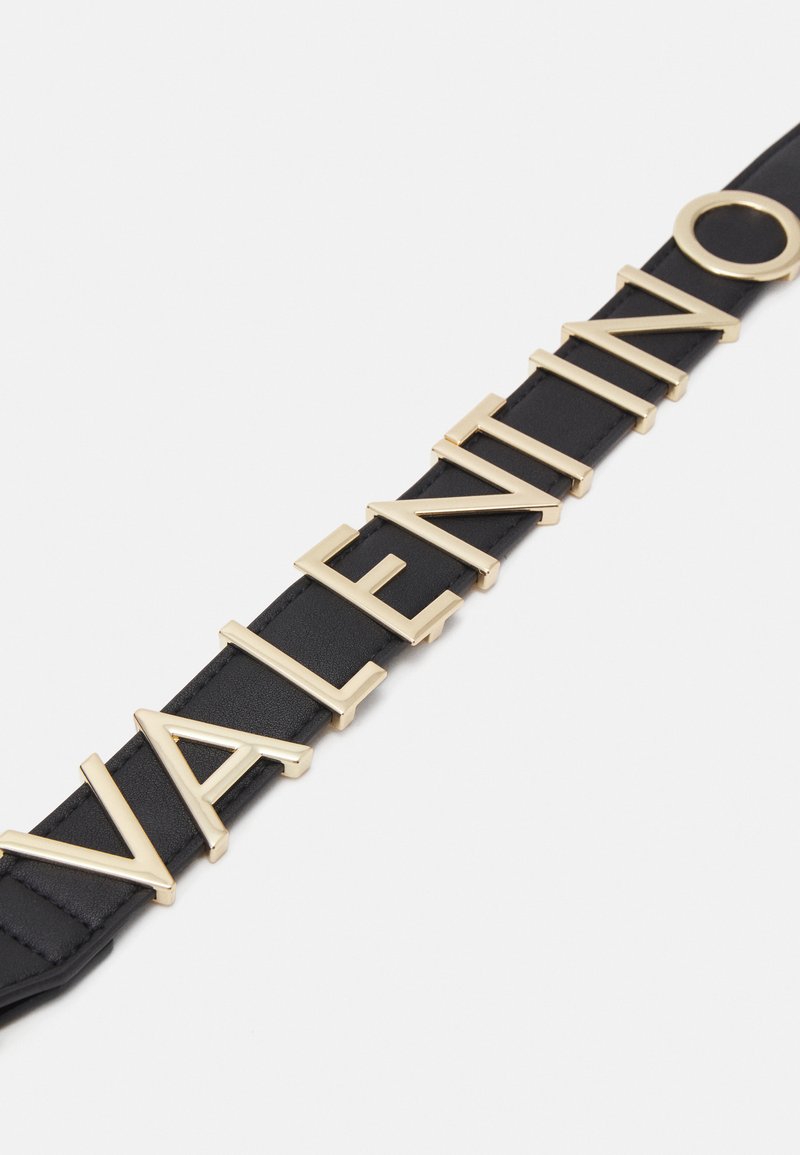 Bracelet en cuir noir avec des lettres en métal doré audacieux formant le mot "VALENTINO," doté d'une texture lisse et d'un design moderne.