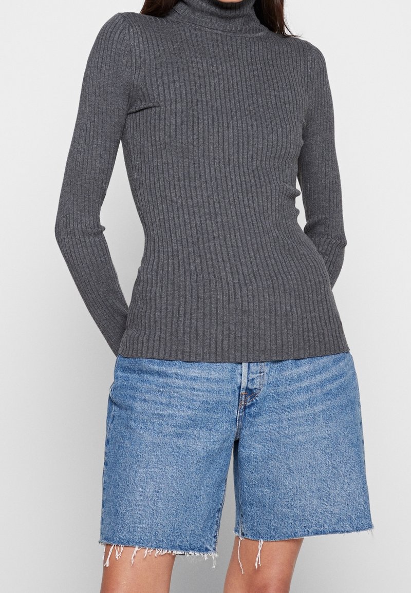 Harmaa ribbineulottu pooloneule pitkine hihoineen, yhdistetty vaaleansinisiin farkkushortseihin, joissa on rispaantuneet reunat. Pehmeä kangas.