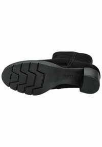 Stivale da caviglia in suede nera con suola piatta, caratterizzato da un battistrada in gomma texture, punta arrotondata e tacco solido per stabilità.