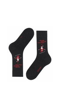 Czarne skarpetki z czerwonymi i białymi wzorami świątecznymi, przedstawiające Świętego Mikołaja na nartach oraz napis "W drodze do domu na święta".