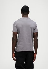 Γκρι κοντομάνικο μπλουζάκι με στρογγυλή λαιμόκοψη, μαλακή υφή και μινιμαλιστικό σχέδιο. Διαθέτει μια διακριτική λεπτομέρεια της μάρκας κοντά στη λαιμόκοψη.