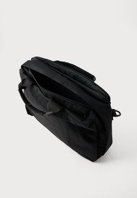 Juodas audinio karinio pašto krepšys su dviem rankenomis ir užtrauktuku. Turi erdvią vidinę dalį ir lygią, tekstūruotą paviršių.