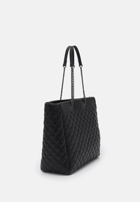 Sac cabas matelassé noir avec un design structuré, doté de doubles anses en cuir et d'accents en chaîne. Texture lisse avec des panneaux contrastants.