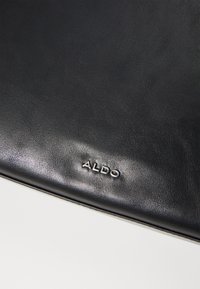 Black leather bag featuring a smooth texture and embossed "ALDO" logo. Simple design with no additional patterns or hardware details.