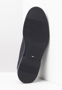 Soletta di scarpa in gomma nera con grip testurizzato, caratterizzata da scanalature orizzontali e logo impresso "Nero Giardini" con dettaglio della bandiera italiana.