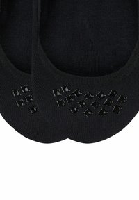 Calzini neri alla caviglia realizzati in materiale elasticizzato, caratterizzati da una superficie liscia e dettagli antiscivolo in un motivo a diamante sulla suola.