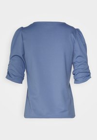 Modrý žebrovaný top s tříčtvrtečními nabíranými rukávy a zaobleným výstřihem. Hladká textura a přiléhavý silueta. Bez viditelných vzorů nebo akcentů.