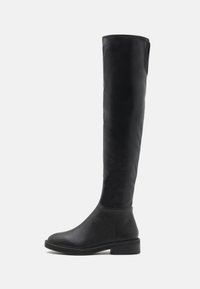 Bota negra por encima de la rodilla hecha de suave cuero sintético con punta redondeada, tacón bajo cuadrado y costuras en contraste a lo largo del borde superior.