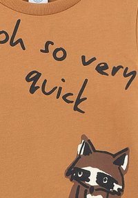 Braunhem shirt mit kurzen Ärmeln und schwarzem Drucktext, der "oh so very quick" sagt, sowie einer Cartoon-Erdmännchen-Illustration unten links.