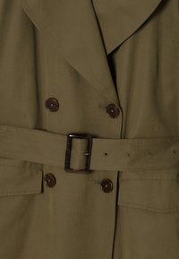 Trench-coat vert olive avec grands revers, devant croisé, boutons marron, taille ceinturée et poches à rabat latérales. Tissu lisse et durable.