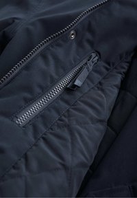 Bolsa de tela acolchada en color marino con un zipper visible, que cuenta con un tirador de zipper a juego y costuras contrastantes en un exterior suave.