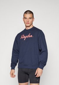 Sudadera azul marino de algodón, con el logo "Rapha." en rosa, cuello redondo, mangas largas y puños y bajo de canalé.